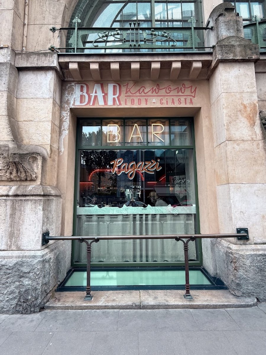 Witryna baru w zabytkowej bramie z neonowym napisem Ragazzi i oryginalnym BAR